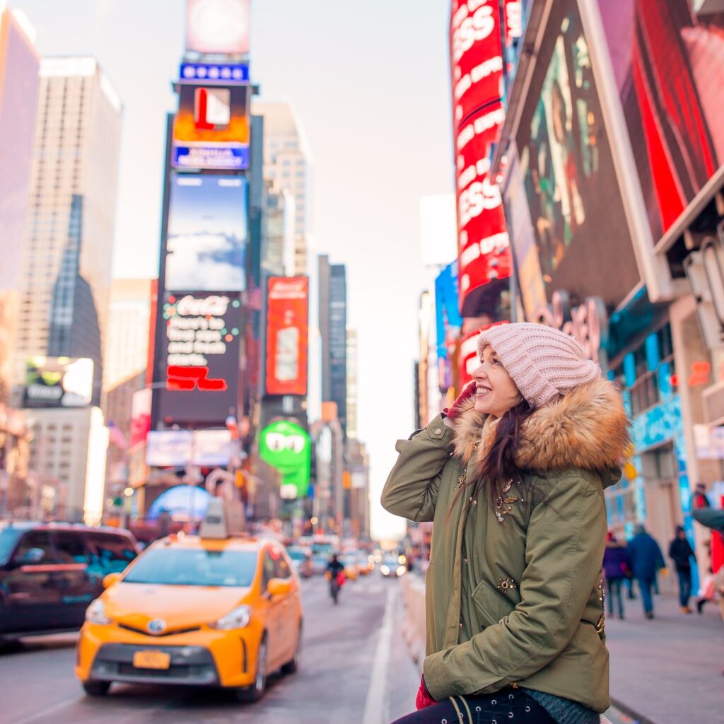 New York City woman on Times Square. Beautiful young happy smiling girl on Manhattan, New York City