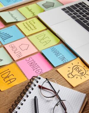 paper stickers with business strategy, laptop and notebook with pencil on tabletop