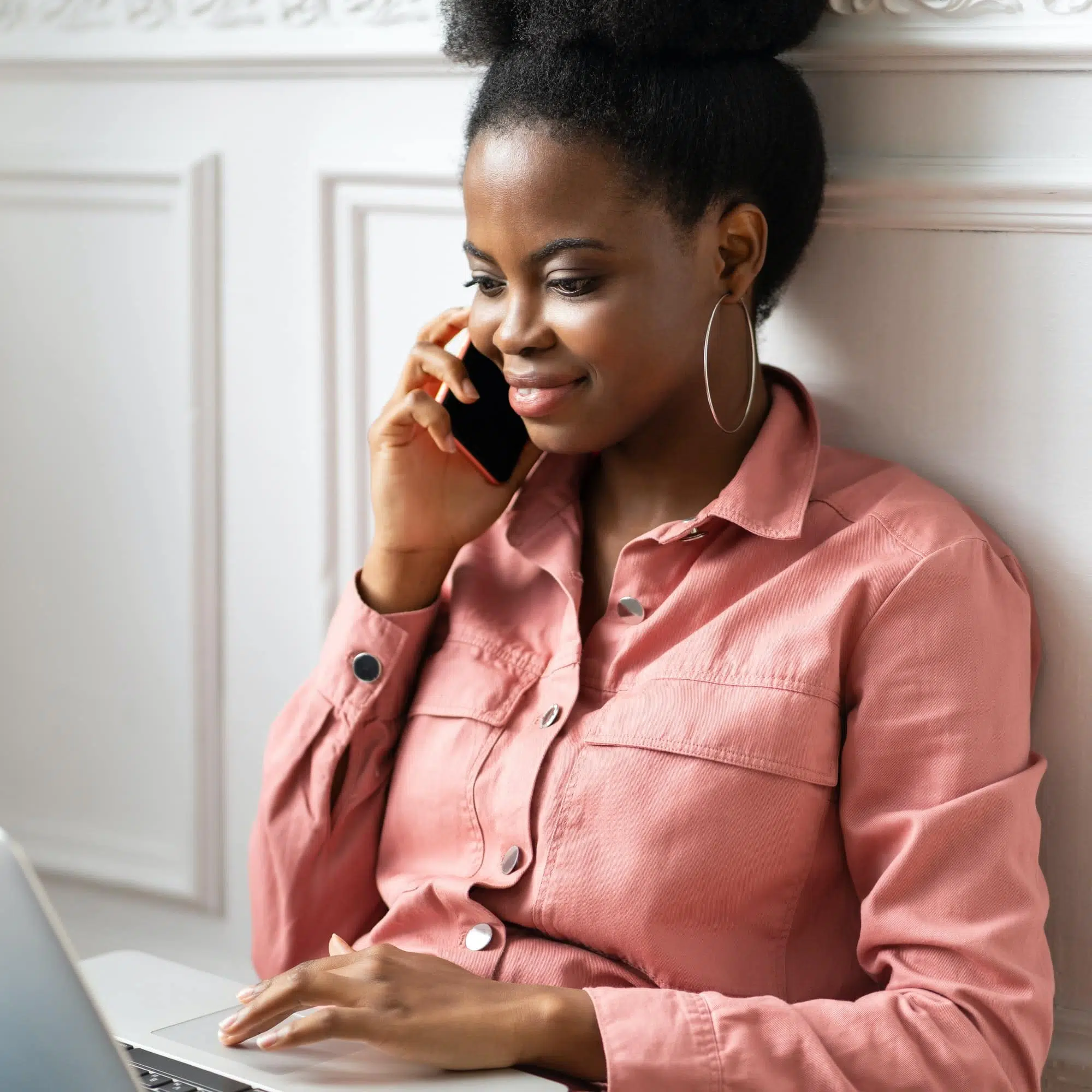 Customer Support & Customer Retention african american millennial woman talking on cellphone working on laptop at home