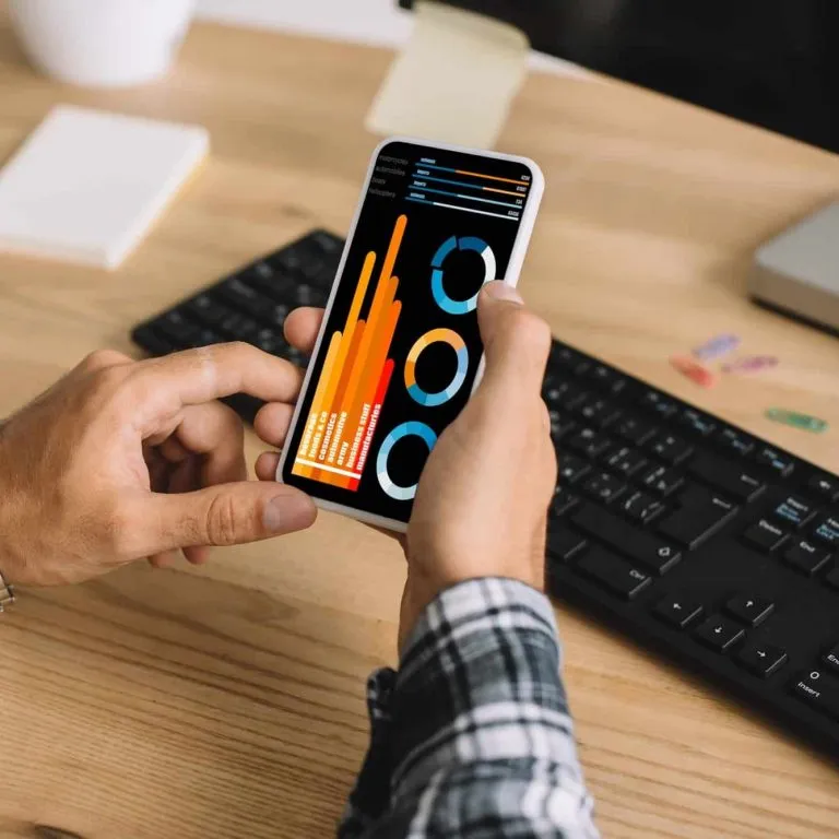 Search Engine Optimization (SEO) cropped shot of seo using smartphone with statistics charts on screen at workplace e1629955546992 1