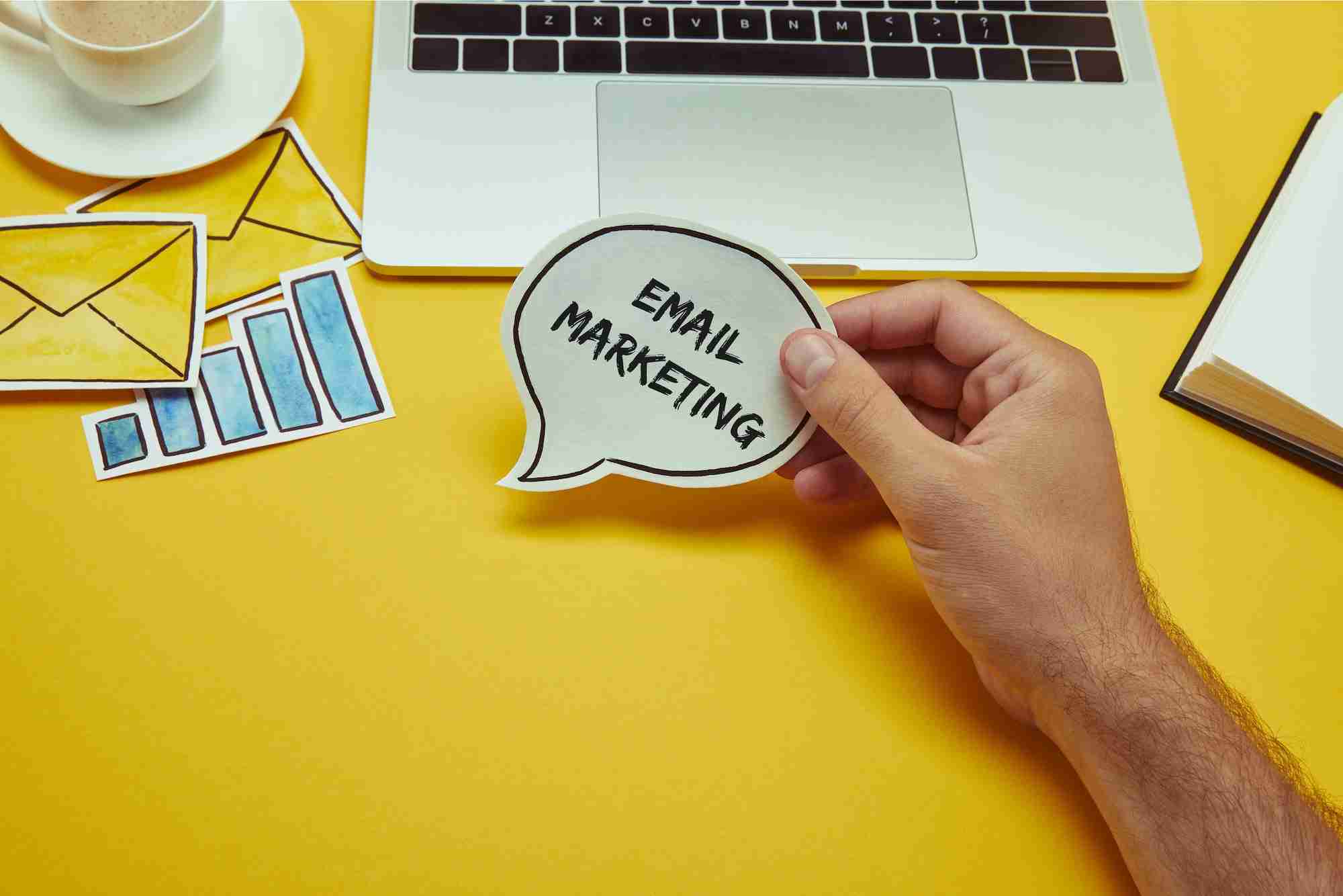 How to send the best B2B email marketing? cropped image of man holding speech bubble with email marketing lettering near laptop