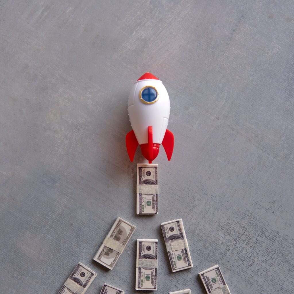 Rocket blasts off through a pile of money.